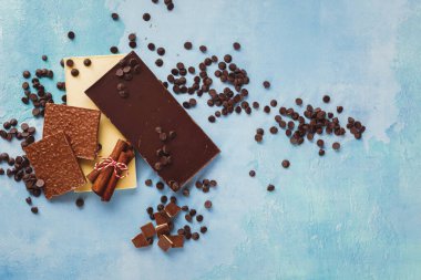 Çeşitli çikolata türleri, tarçın ve koyu çikolata parçacıkları. Çeşit çeşit siyah, beyaz ve sütlü çikolatalar, kısmen kırılmış. Üst görünüm, boş boşluk