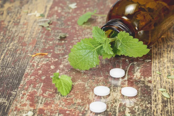 Citronmeliss. Flaska med tabletter och naturläkemedel på träbord — Stockfoto