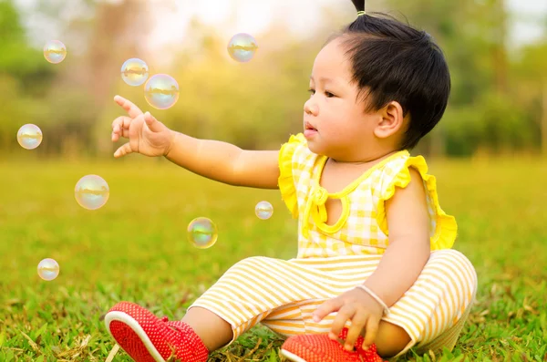 Aziatische baby gelukkig in het gras met zonlicht tijdig's ochtends. Stockfoto