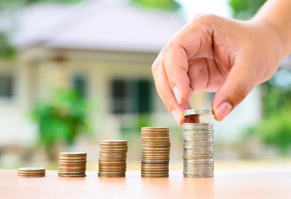 Mão masculina colocando moedas de dinheiro para empilhar com casa em economia para o conceito de casa — Fotografia de Stock