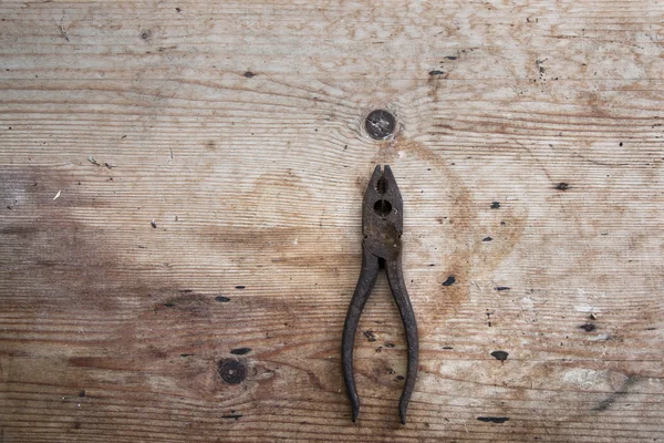 Old rusty pliers on the dirt wooden desk Royalty Free Stock Photos