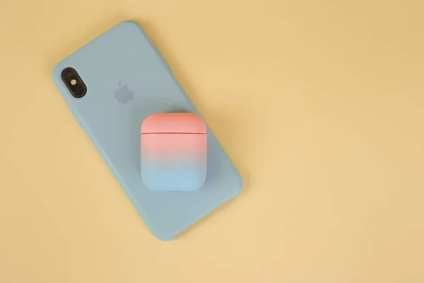 Silikon bir çantada telefon ve sarı arka planda kulaklık kutusu ve mesaj için yer var. Şık bir telefon ve kulaklık. Kadın aygıtları