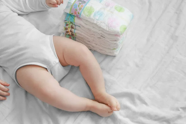 Babyfüße Und Eine Packung Windeln Auf Einem Weißen Bett Schmutzige — Stockfoto