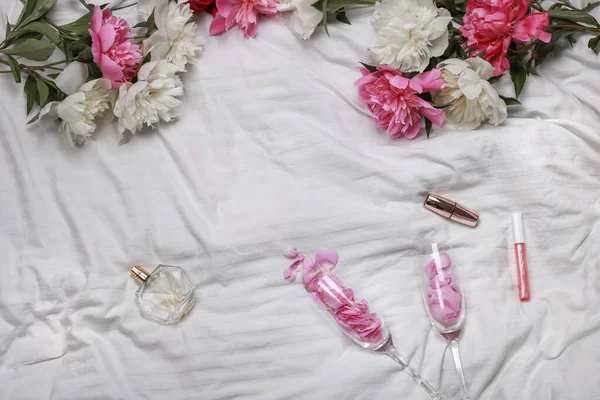 Beyaz Bir Yatakta Kadın Kıyafetleri Şakayık Parfüm Ruj Kadın Cihazları — Stok fotoğraf