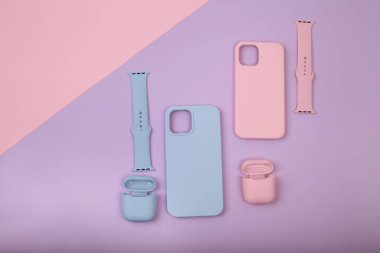 Renkli silikon telefon kılıfları, saat kayışı ve kulaklıklar için çantalar. Hazır ol. Güncel teknoloji. Çok şık. Mor arka planda yatan çeşitli kişisel aksesuarları kapat, düz uzan