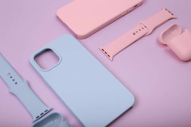 Renkli silikon telefon kılıfları, saat kayışı ve kulaklıklar için çantalar. Hazır ol. Güncel teknoloji. Çok şık. Mor arka planda yatan çeşitli kişisel aksesuarları kapat, düz uzan