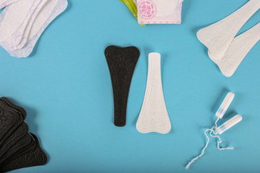 Siyah ve beyaz arasında bir seçim. Mavi arka planda regl tamponları ve pedler. Adet döngüsü. Hijyen ve koruma. Düz yatıyordu. Metin için kopyalama alanı ile.