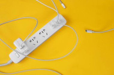 Sarı arka planda prizleri olan şık beyaz elektrik genişleticisi. Elektrik güç beyaz şeridi ya da uzatma bloğu. Bir sürü kablo ve oyuk. Yüksek teknoloji akıllı şerit. Kopyalama alanı ile düz uzandı