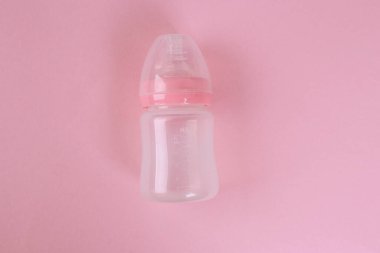 Pembe arka planda bebek şişesi. Planlı çocuklar. Fotokopi alanı olan düz bir yer. O bir kız.!