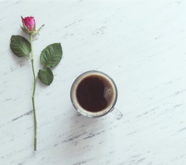 Fincan kahve ve mermer zemin üzerine pembe bir gül