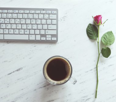Çalışma alanı klavye, bir fincan kahve ve bir gül ile