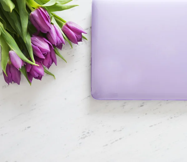 Computer with bouquet of purple tulips — Stock Photo, Image