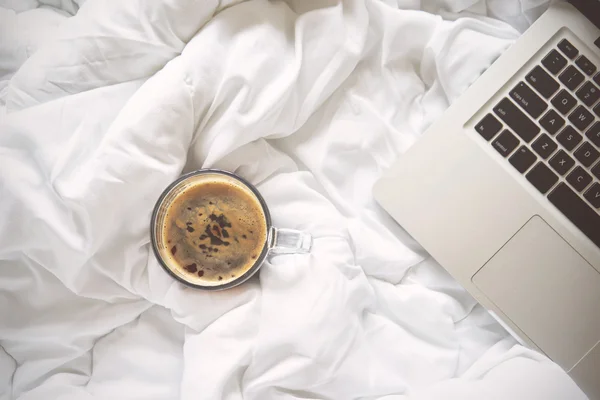 ベッドやラップトップ、白いベッドの上のコーヒー カップでください。 — ストック写真