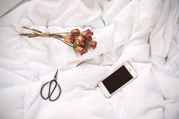 마른 장미, 스마트폰 및 침대에 빈티지가 위 — 스톡 사진