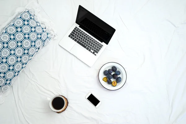 Working in bed , laptop and cup of coffee on white bed