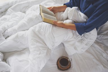 Kitap okuma ve yatakta kahve içme kız