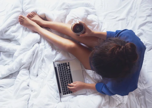 若い女性彼女のベッドで自宅でコーヒーを飲むと、彼女をチェック アウト — ストック写真