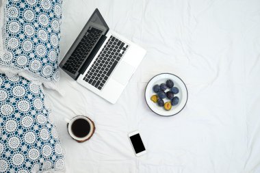 Yatak, dizüstü bilgisayar ve kahve beyaz yatakta çalışma