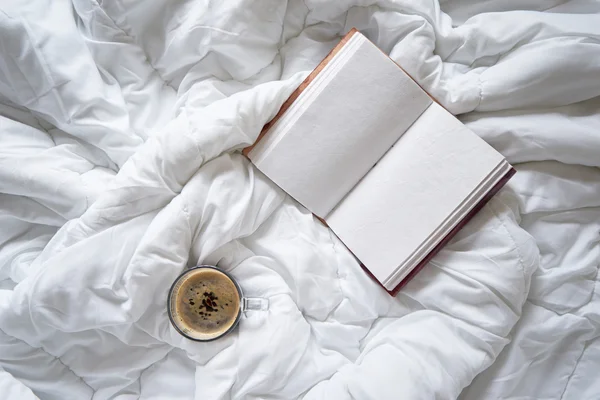 Cup of coffee and vintage notebook on bed — Stock Photo, Image