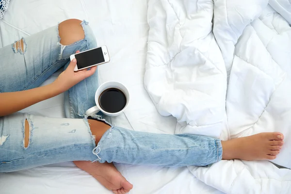 若い女性彼女のベッドで自宅でコーヒーを飲むと、彼女をチェック アウト — ストック写真
