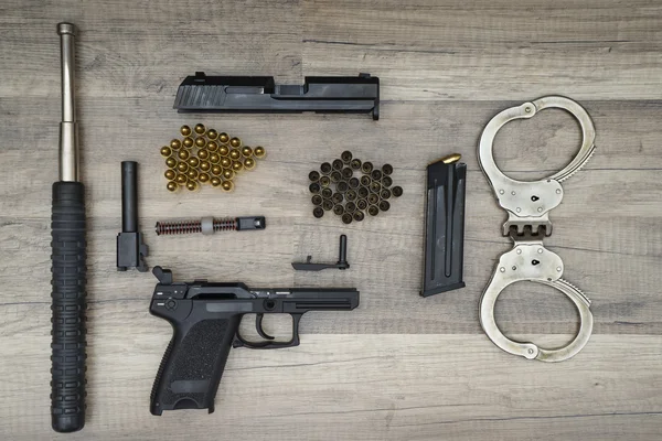 Gun pistool met nieuwe en gebruikte opsommingstekens, vleermuis politie en handboeien — Stockfoto