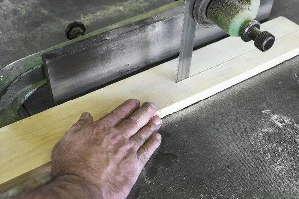 Carpenter cutting piece of wood with bandsaw in workshop — Stock Photo, Image