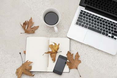 Dizüstü bilgisayar, akıllı telefon fincan kahve ve halı üzerinde bulunan not defteri