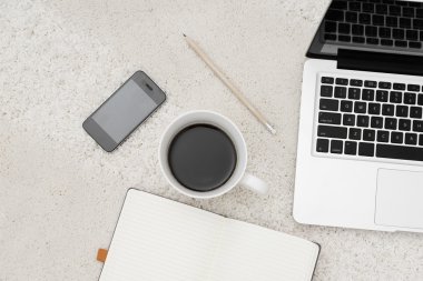 Dizüstü akıllı telefon fincan kahve ve halı üzerinde bulunan not defteri 