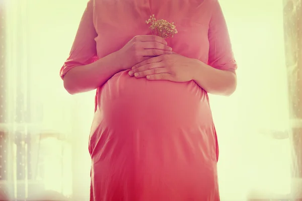 Nahaufnahme auf dem Bauch einer schwangeren Frau, hält in den Händen Strauß von f — Stockfoto