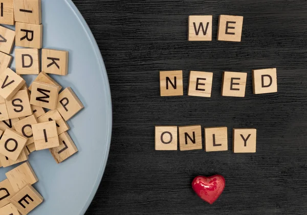 Wooden letters spelling we need only love — Stock Photo, Image