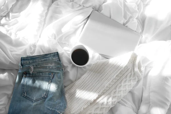 Female outfit, a  cup of coffee and a laptop laid out on bed, mo — Stock Photo, Image