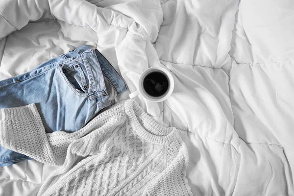 Жіноче вбрання і чашка кави викладена на ліжку, ранкове світло — стокове фото