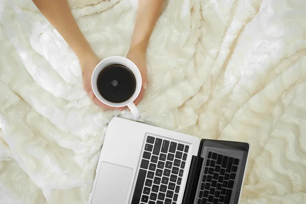 ベッドにホット コーヒーのカップを保持している女性の手 — ストック写真
