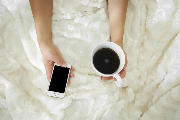 젊은 여 자가 그녀의 침대에서 집에서 커피를 마시는 그녀의 검사 — 스톡 사진