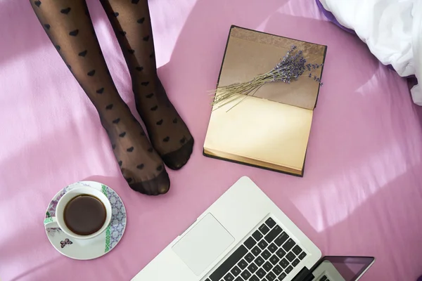 Mulher na cama com laptop, notebook e xícara de café — Fotografia de Stock