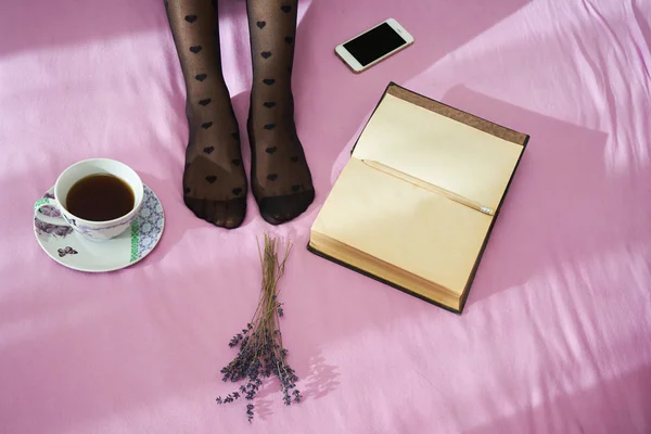 Kadın yatakta smartphone, defter ve kahve