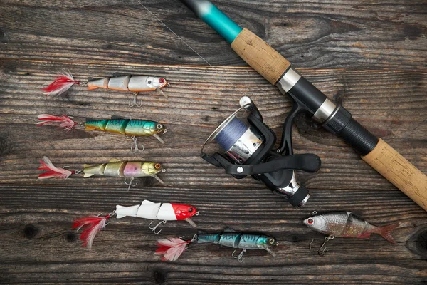 Spinning rod, reel and fishing baits isolated on wooden backgrou — Stock Photo, Image