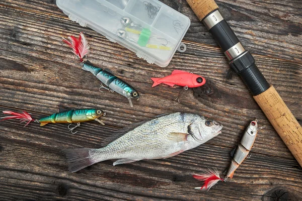 Caña giratoria, carrete y cebos de pesca aislados en el fondo de madera —  Fotos de Stock