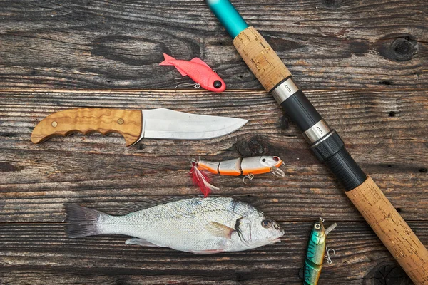 Caña giratoria, carrete y cebos de pesca aislados en el fondo de madera —  Fotos de Stock