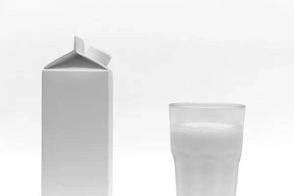 Boîte à lait blanche et un verre de lait, sur fond blanc — Photo