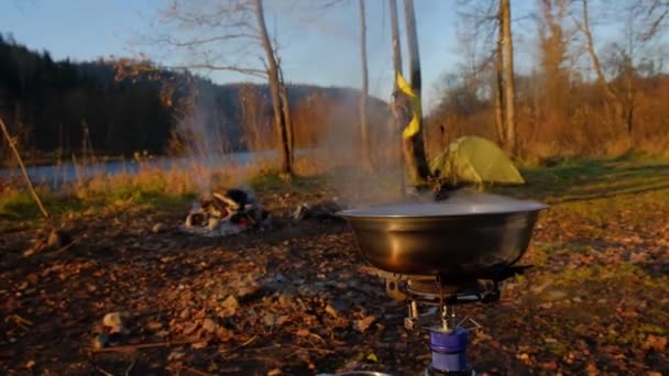 在靠近河边的远足条件下烹调旅游食品 — 图库视频影像