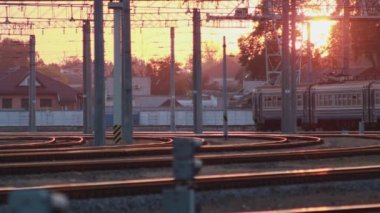 Russain yolcusu elektrikli çoklu tren gün batımında istasyondan ayrılıyor. Yolcular platformda yürüyor. Seyahat ve turizm. Demiryolu vagonları gündüz gidiyor..
