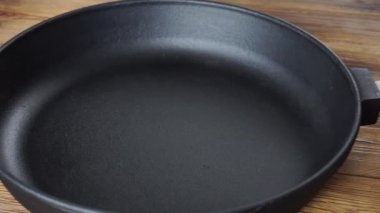 Tahta arka planda çıkarılabilir ahşap saplı demir kızartma tavası. Her türlü ocak, ev ve mutfak için uzun süreli yemek tepsisi.