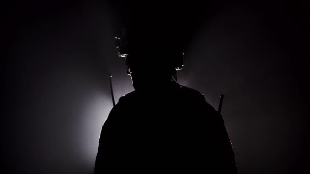 Militär soldat i militär utrustning med ett skjutvapen i rök på svart bakgrund. Bakgrundsbelysning, militära operationer — Stockvideo