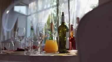 Parti için güzel bir oda, masa takımı, bardaklar, konyak şişeleri, şarap. Tatil için masa dekorasyonu, pencerede güneş.