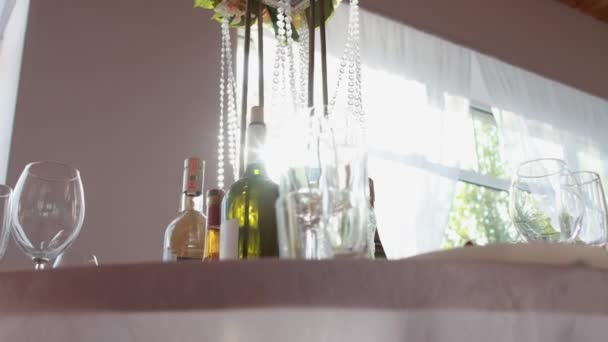 Красивая сервировка стола на банкете, бутылки с алкогольными стаканами стоят на украшенном столе на фоне солнца — стоковое видео
