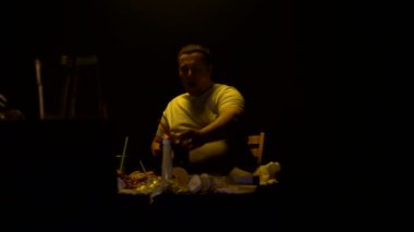 Şişman, dağınık bir adam evde TV karşısında oturur ve fast food yer. Yanlış ve yağlı yemek konsepti, oburluk.