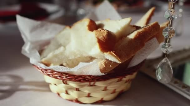 Schaal met gesneden wit brood op de achtergrond van zonnestralen, close-up — Stockvideo