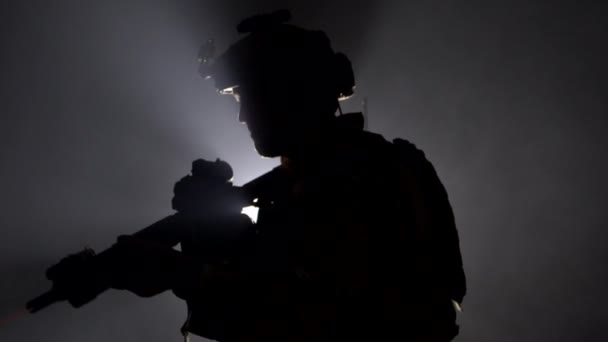 Soldat militaire avec un fusil dans les mains et une vue laser sur un fond noir en contre-jour. Le concept de guerre et d'hostilités, au ralenti — Video