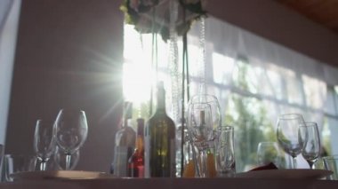 Parti için güzel bir oda, masa takımı, bardaklar, konyak şişeleri, şarap. Tatil için masa dekorasyonu, pencerede güneş.